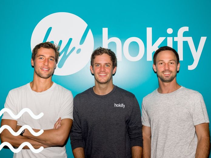 Die hokify Co-Gründer Karl Edlbauer, Daniel Laiminger und Simon Tretter vor dem hokify Logo