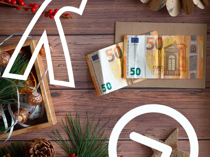 Weihnachtsgeld: Zwei 50€ Scheine auf einem Weihnachtlich dekorierten Holztisch