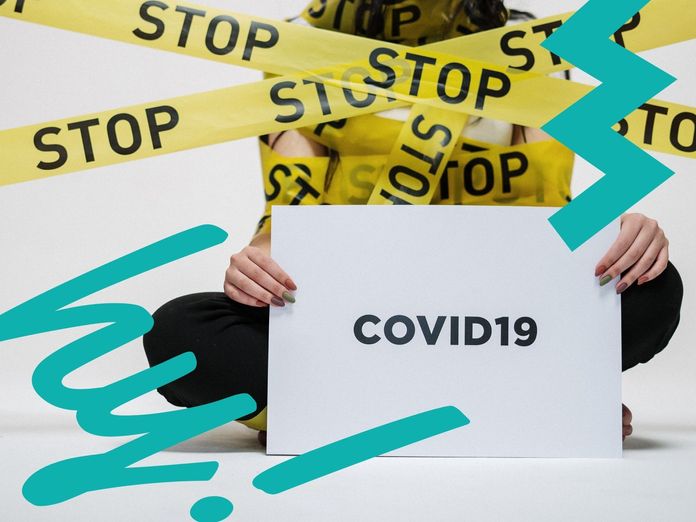 Absperrband rund um eine Frau die ein "COVID19"-Schild hält