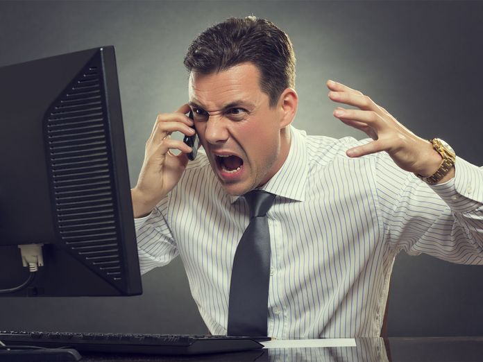 Frustrierter Mann ärgert sich am Telefon über seinen Job.