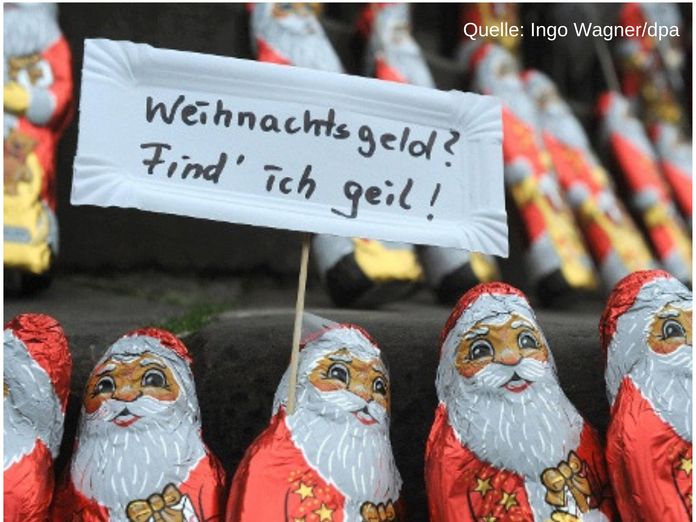 Schokolade Weihnachtsmänner halten Schild mit Aufschrift: Weihnachtsgeld? Find ich geil! (Quelle: Ingo Wagner/dpa)